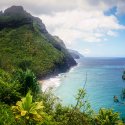 Bright blue ocean runs long a grassy, volcanic cliff in Hawaii