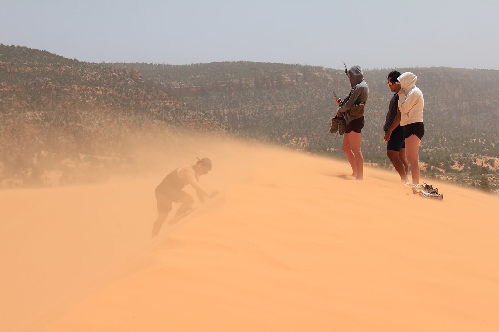 The pink sand dunes, with blowing winds and four people enjoying the view.