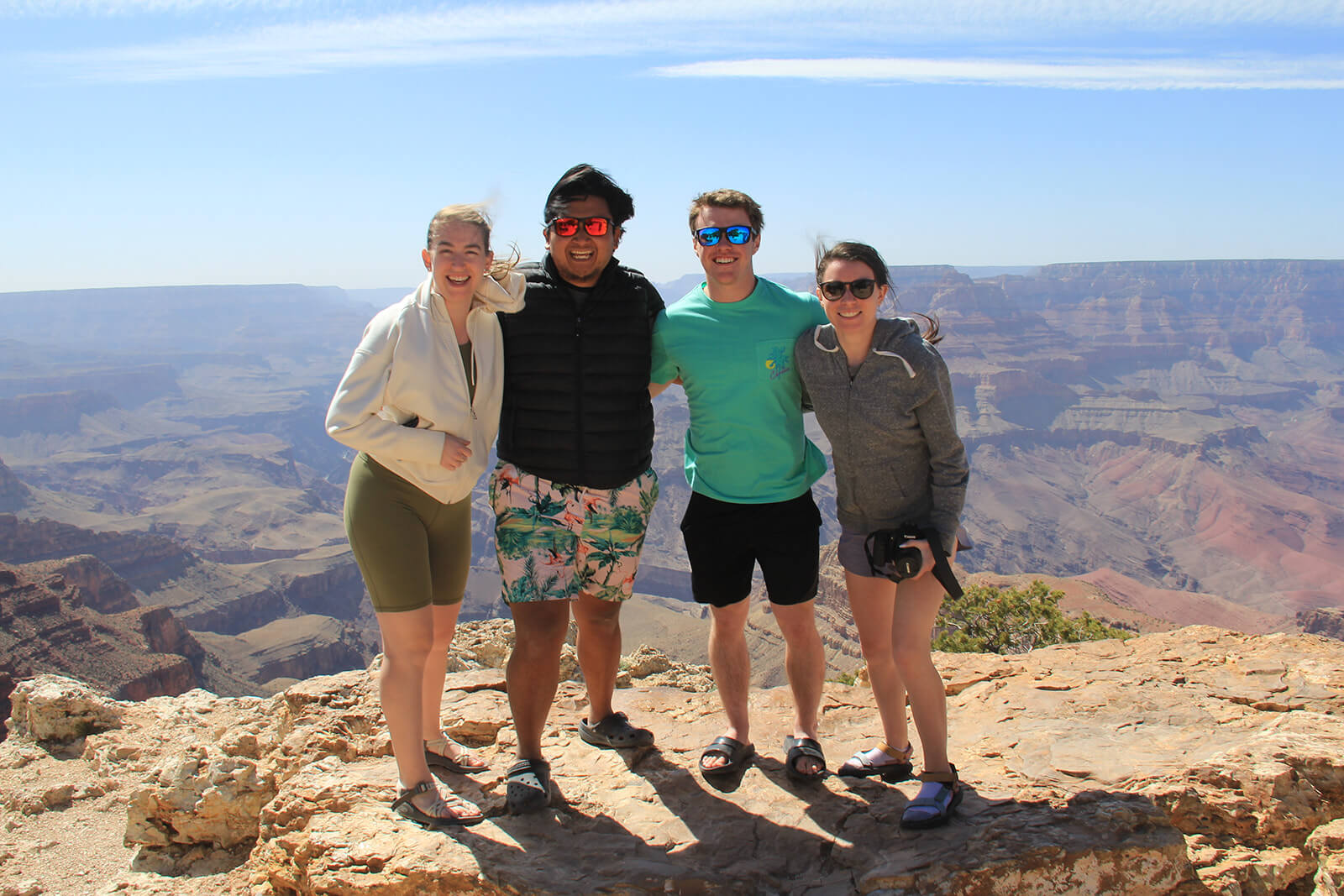 Photo of four people posing in front of a canyon.