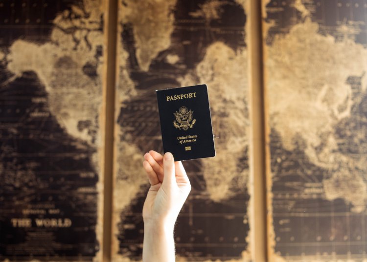 Passport held up in front of a map of the world
