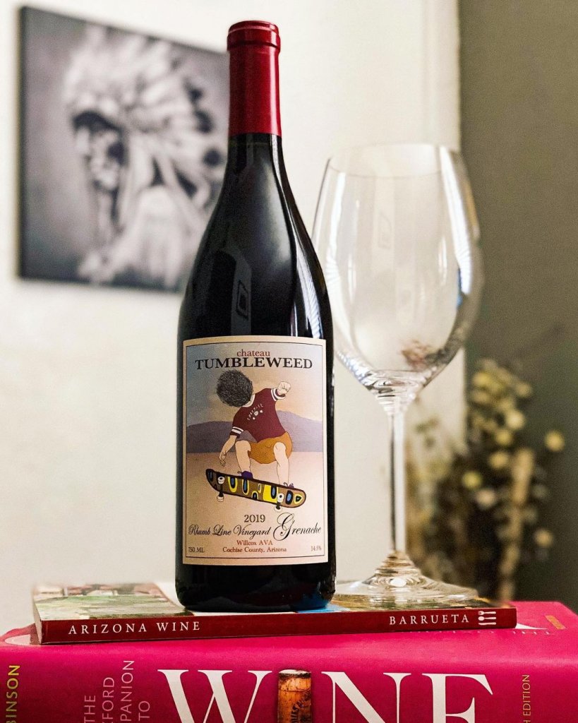 A bottle of 2019 wine from Chateau Tumbleweed in Clarkdale, Arizona sits atop a pile of wine books.