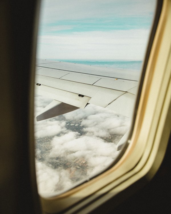 Looking out the window of an airplane at the wing and clouds in view.