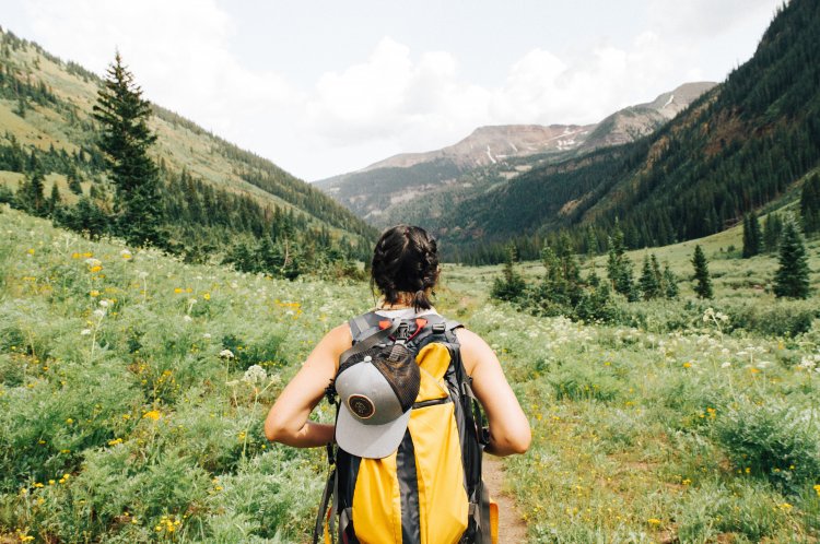 Woman seen from behind, with hiking gear, looking out across a valley. 