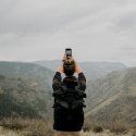 Person taking a photo of a mountain and valley on a cloudy day.
